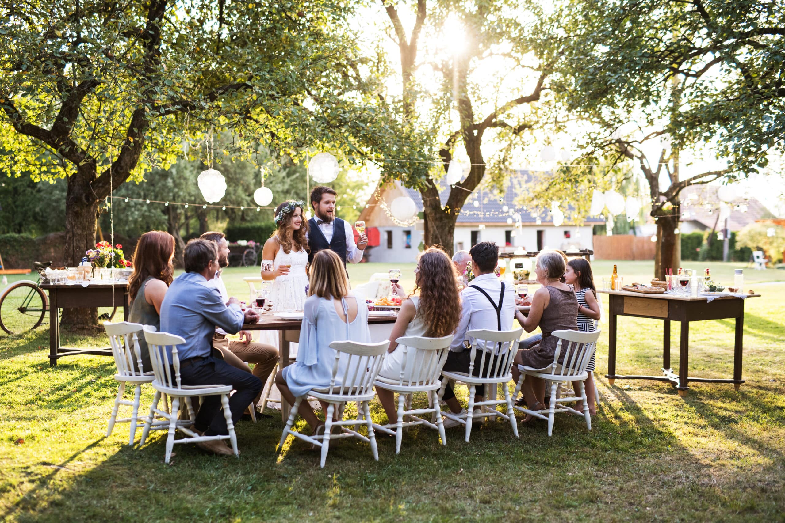 bride and groom with guests at wedding reception outside in the backyard.